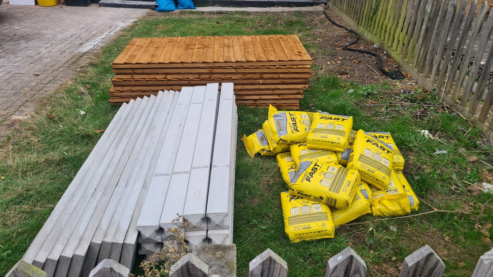 Stack of concrete posts, bags of postmix and concrete gravel boards professionally delivered by Romford Fencing Ltd