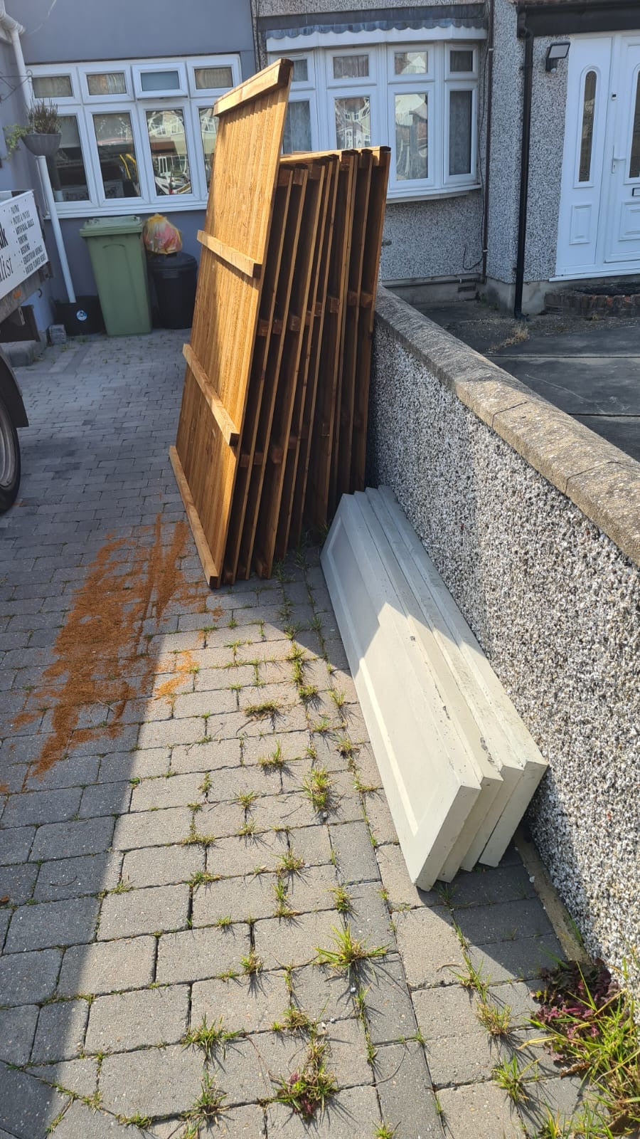 Stack of wooden panels and concrete gravel boards on a driveway next to a house delivered with a 5 star service by Romford Fencing Ltd